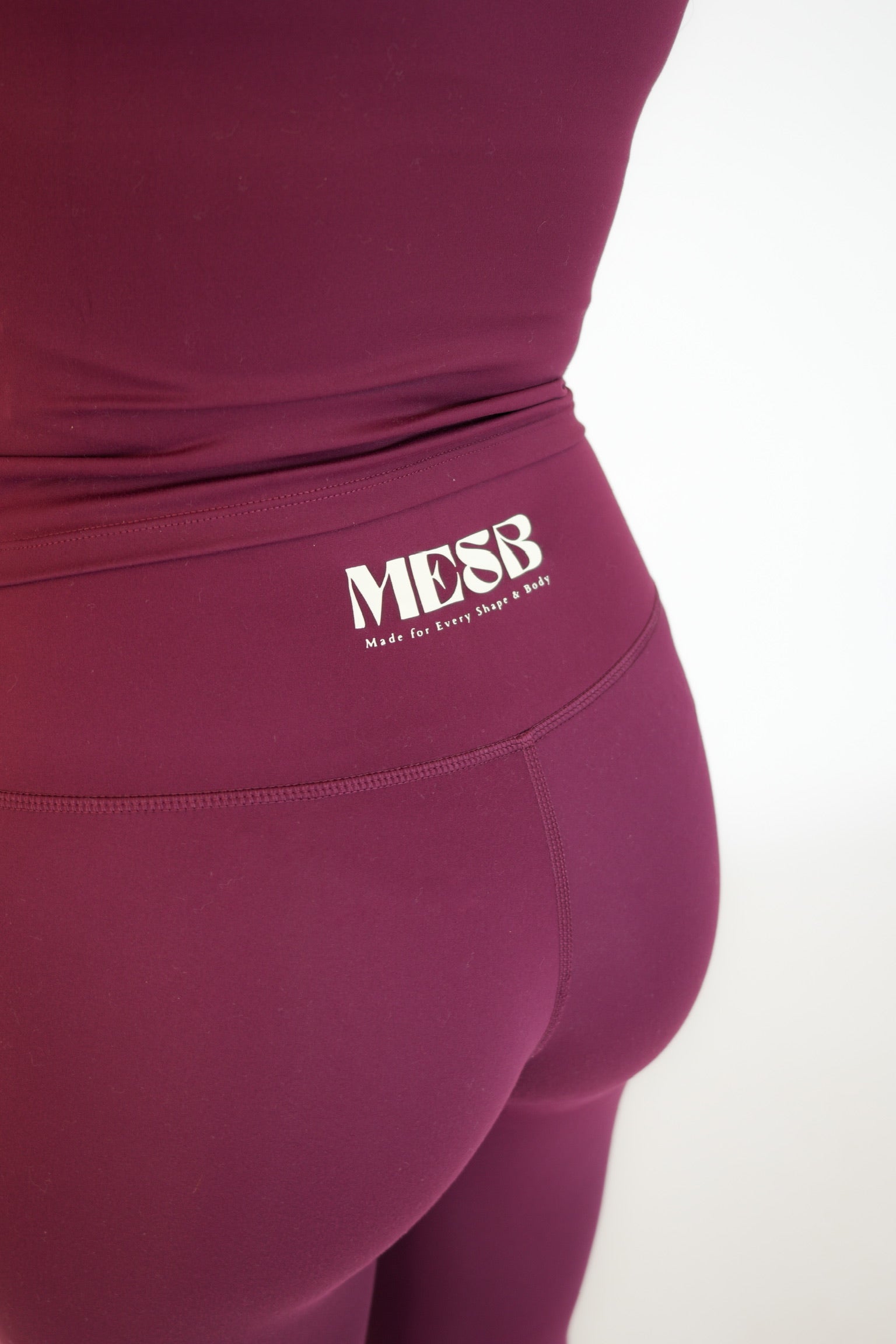 A close up of the back of a model wearing the Garnet glow MESB leggings. The photo is zoomed into the logo