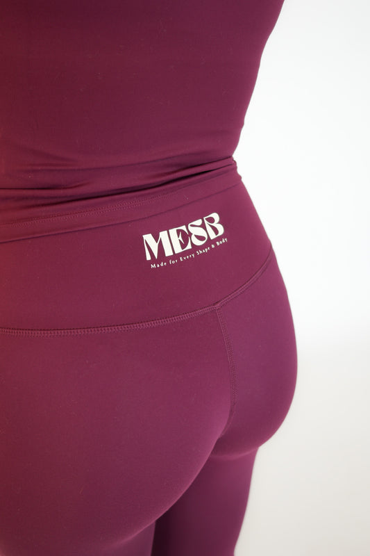 A close up of the back of a model wearing the Garnet glow MESB leggings. The photo is zoomed into the logo