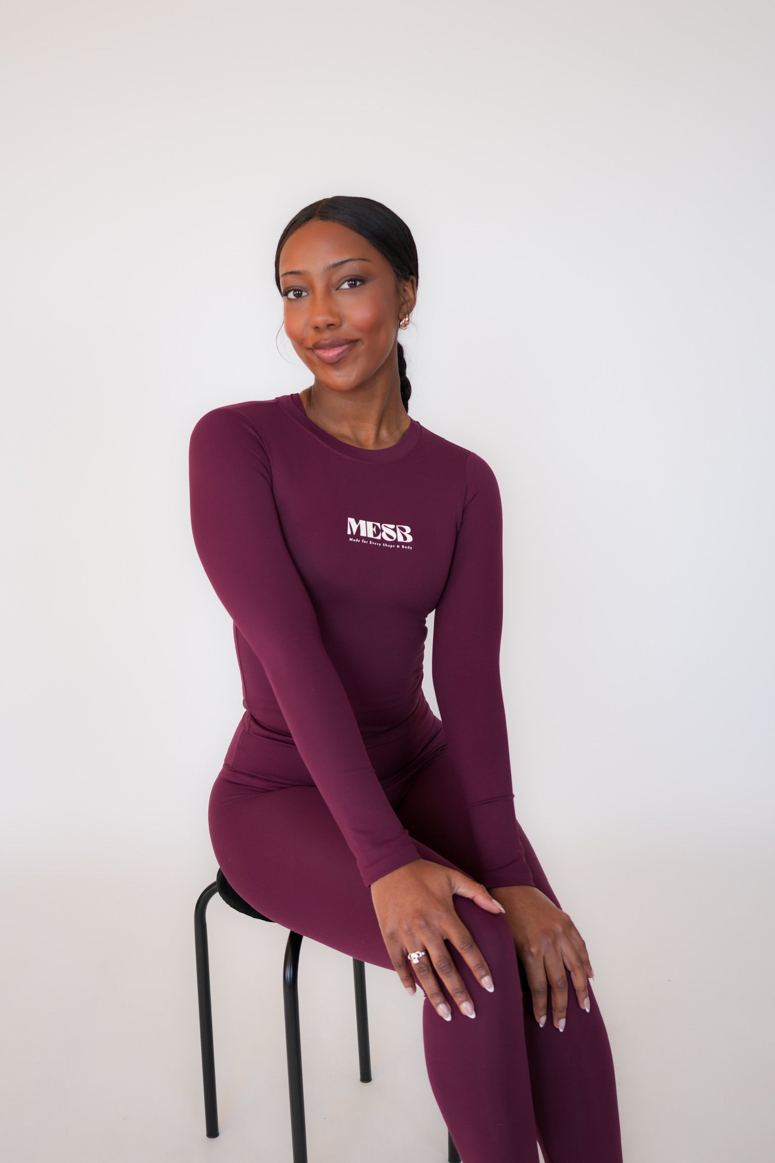 Model sitting on black chair with a white background wearing the long sleeve Garnet glow MESB set