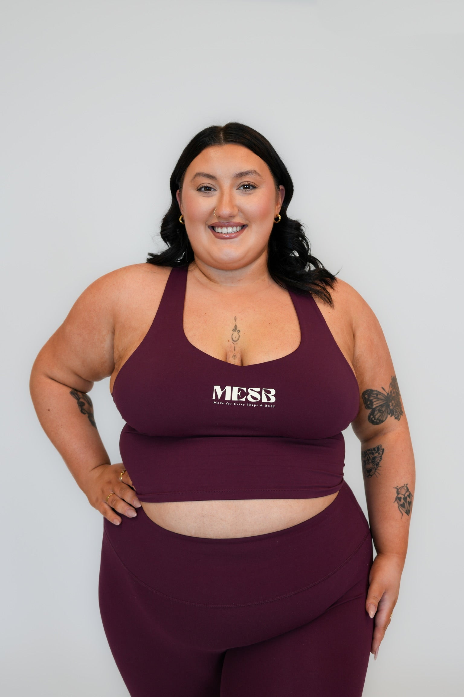 Close up of model wearing Garnet glow tank top MESB set with her hand on her hip